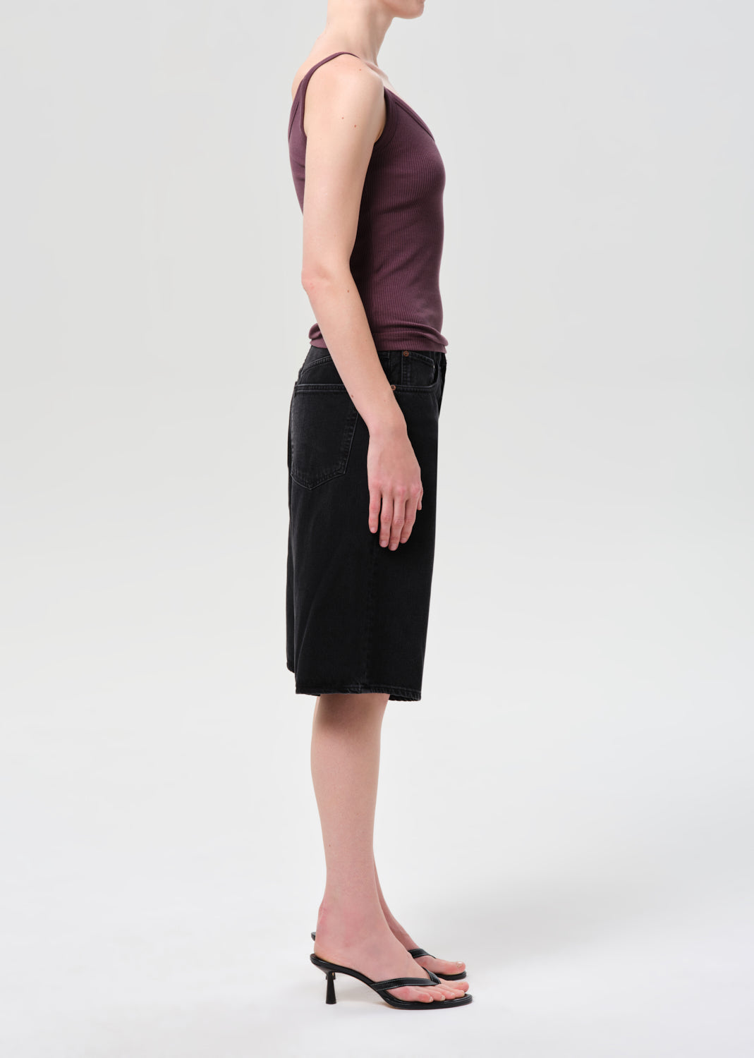 Person wearing a sleeveless purple top and black skirt on a white background
