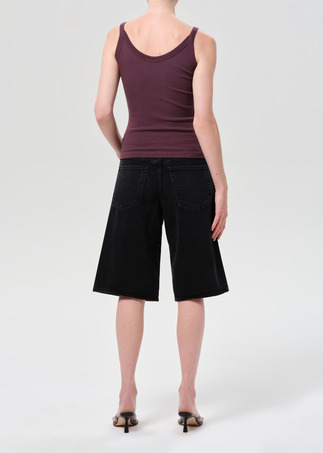 Person wearing a purple tank top and black shorts on a white background