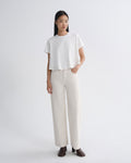 Woman wearing a white t-shirt and beige pants on a plain background
