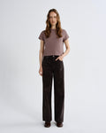 Woman wearing a brown t-shirt and black pants on a white background