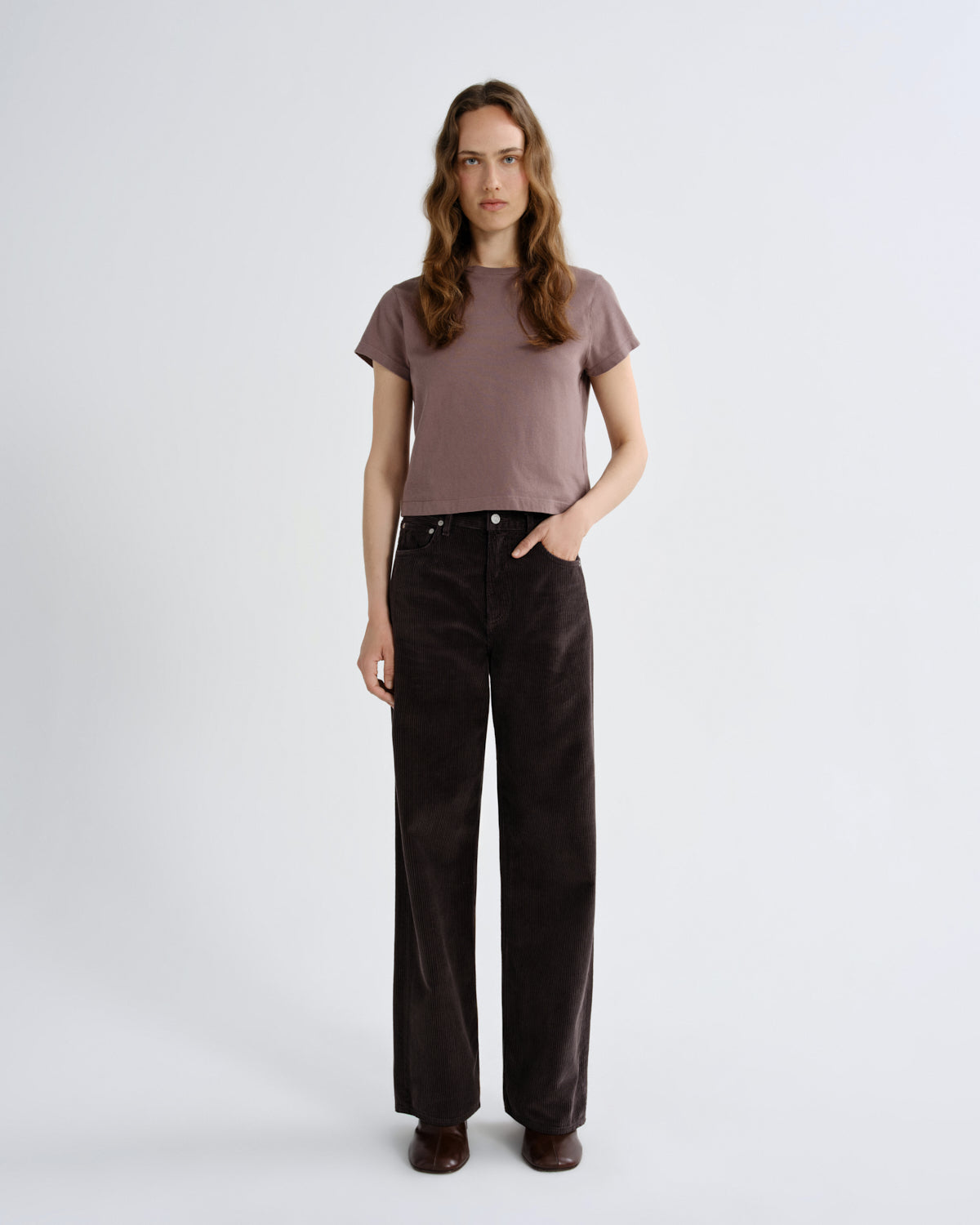 Woman wearing a brown t-shirt and black pants on a white background