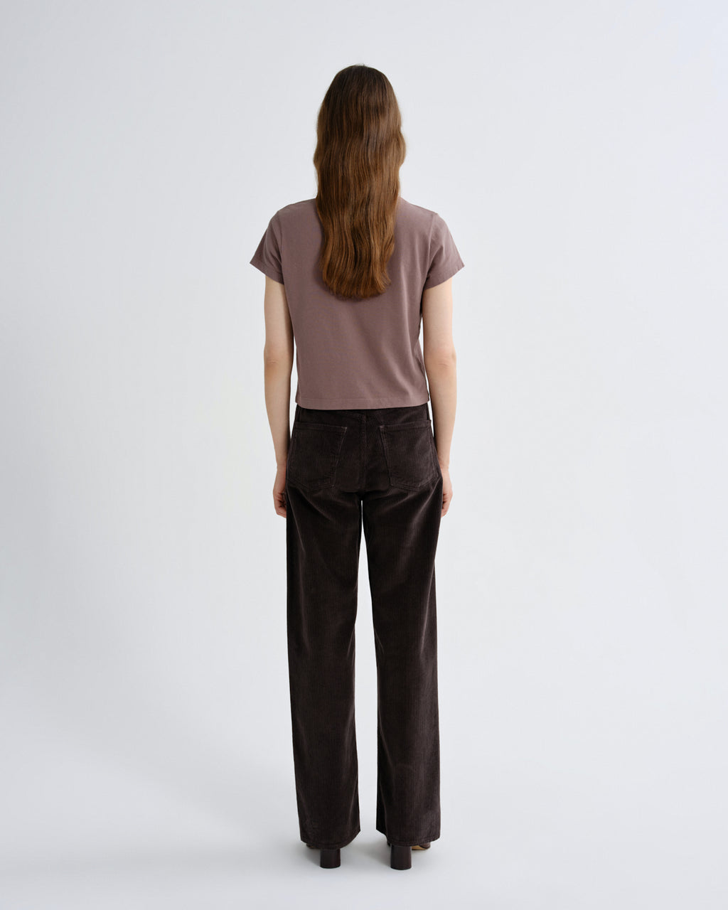 Woman wearing a brown t-shirt and dark brown pants on a white background