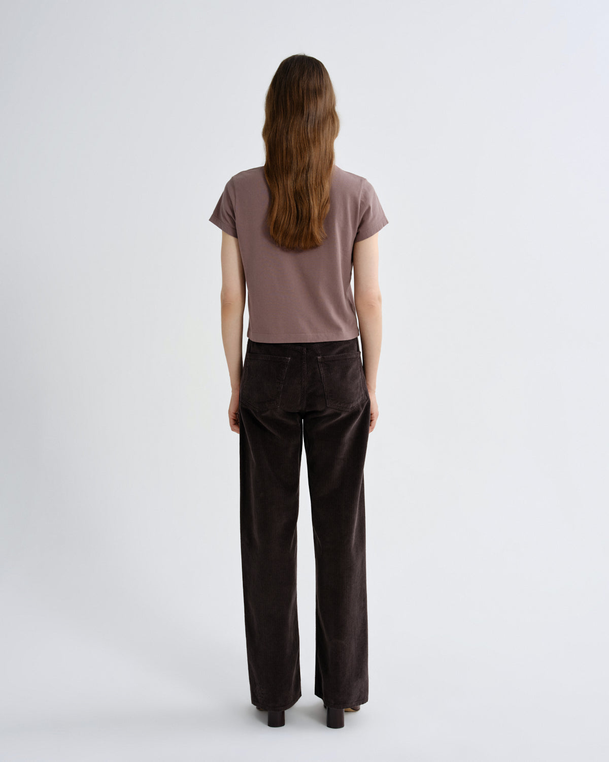 Woman wearing a brown t-shirt and dark brown pants on a white background