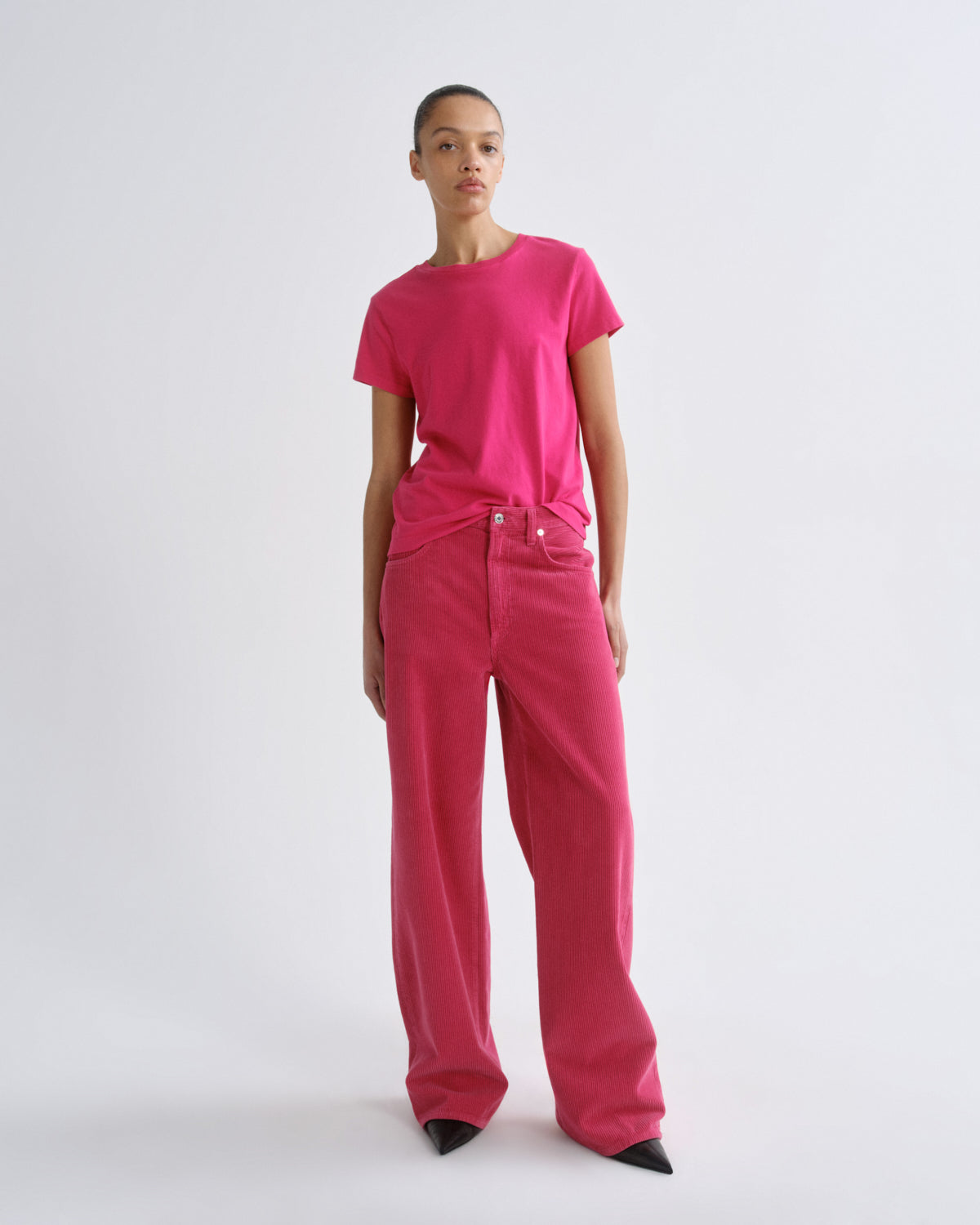 Person wearing a bright pink outfit on a white background