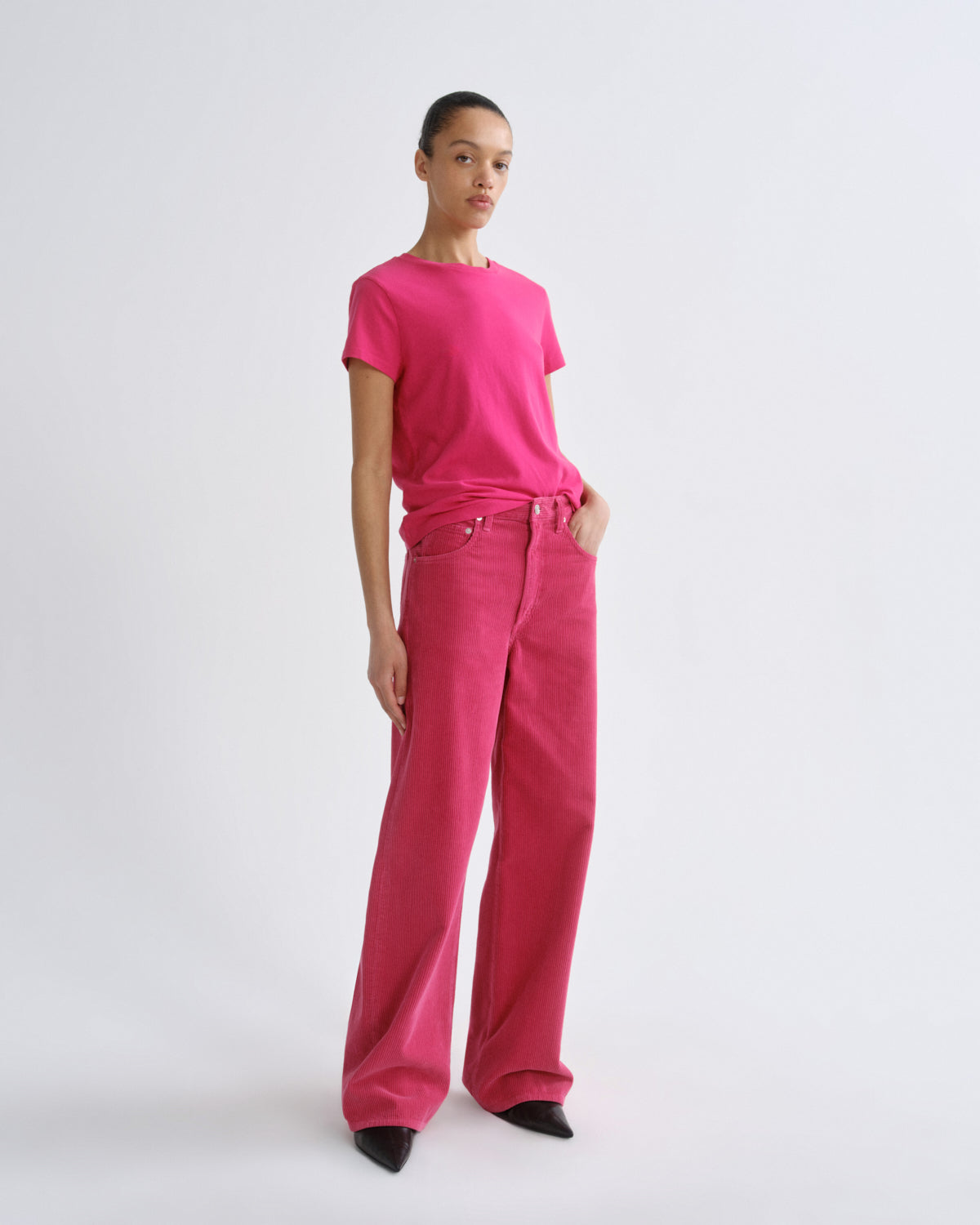 Person wearing a bright pink t-shirt and pants on a white background