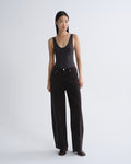 Woman wearing a black tank top and wide-leg pants on a white background