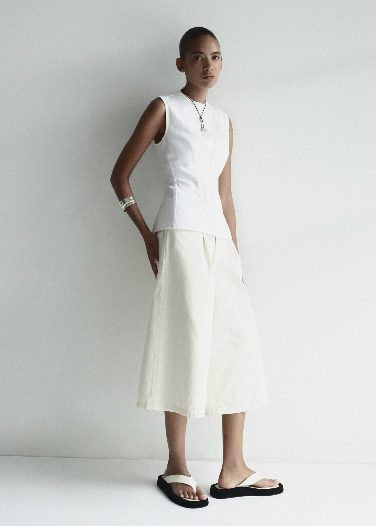 Person wearing a white sleeveless top and skirt set against a plain background