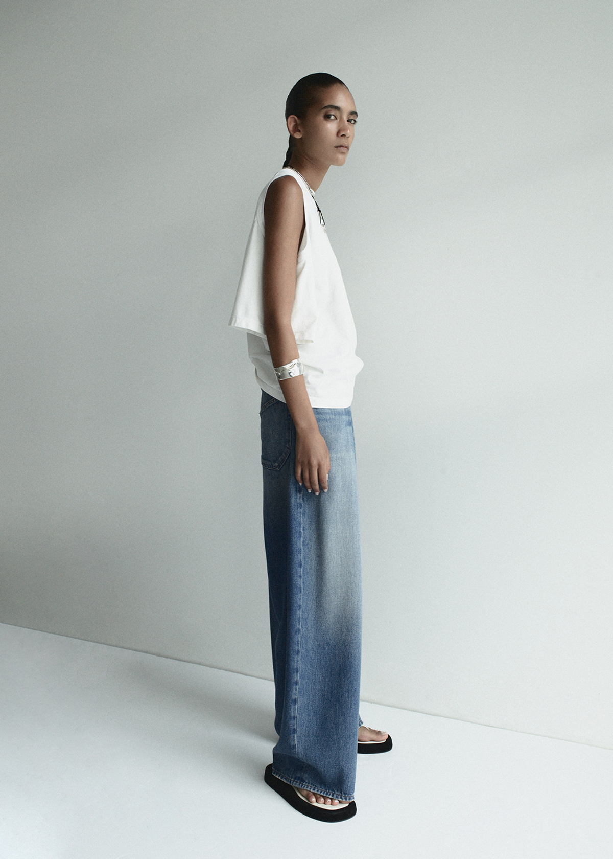 Person wearing a white top and blue jeans against a plain background