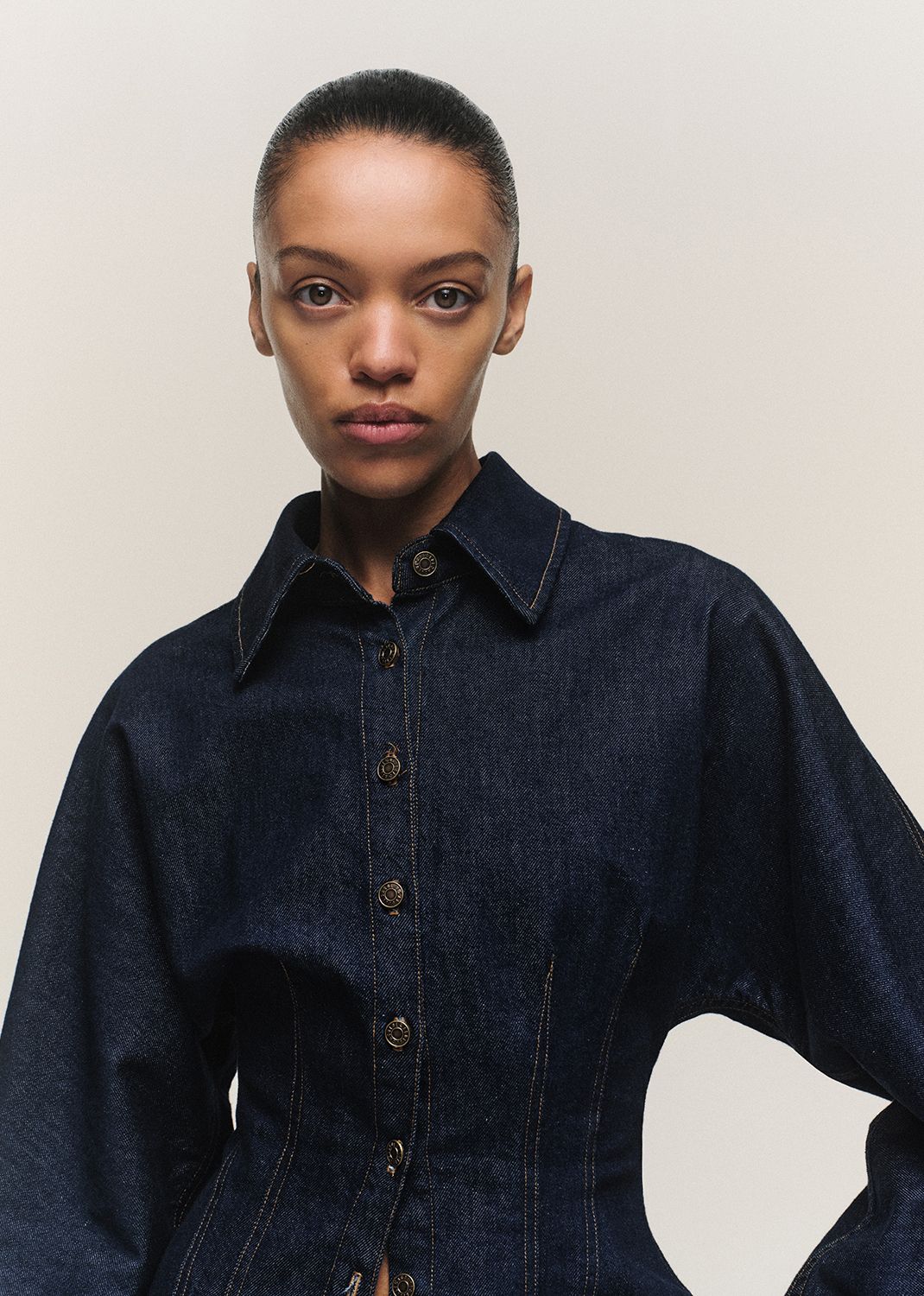 Person wearing a dark denim shirt against a plain background