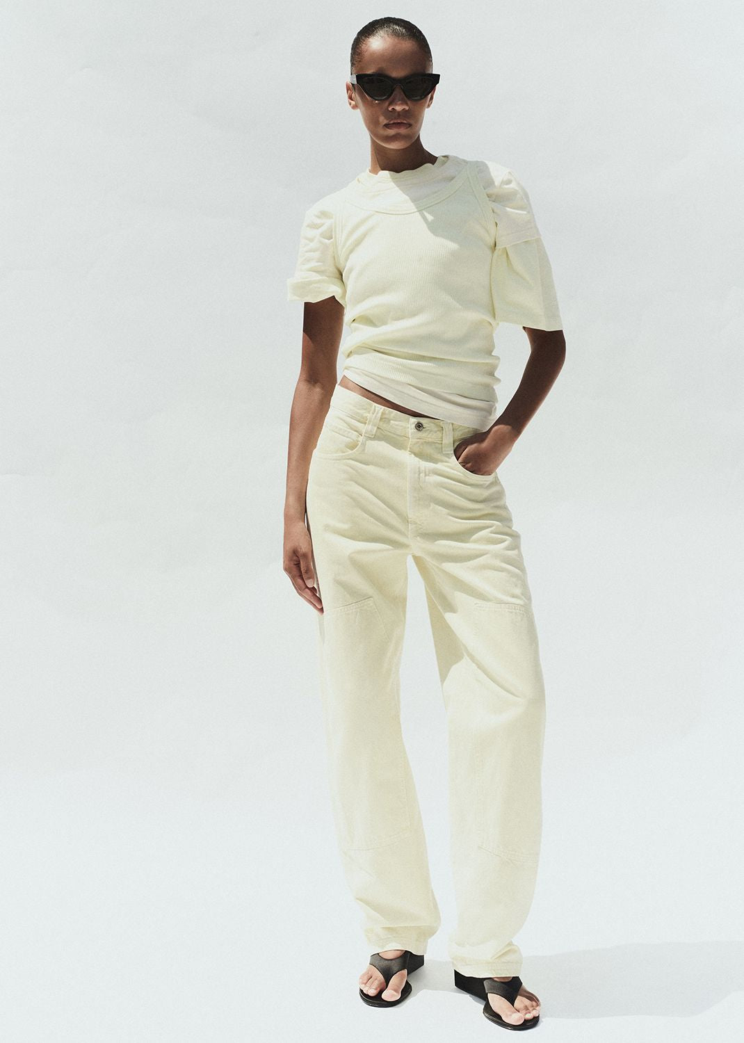 Person wearing a white outfit with sunglasses on a plain background