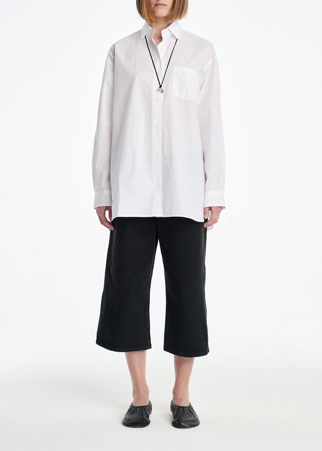 Person wearing a white shirt and black pants on a white background