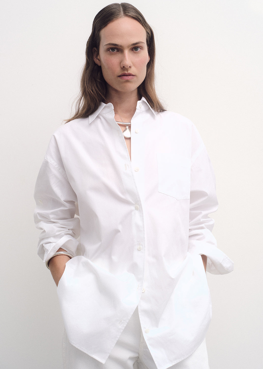 Person wearing a white oversized shirt against a plain background