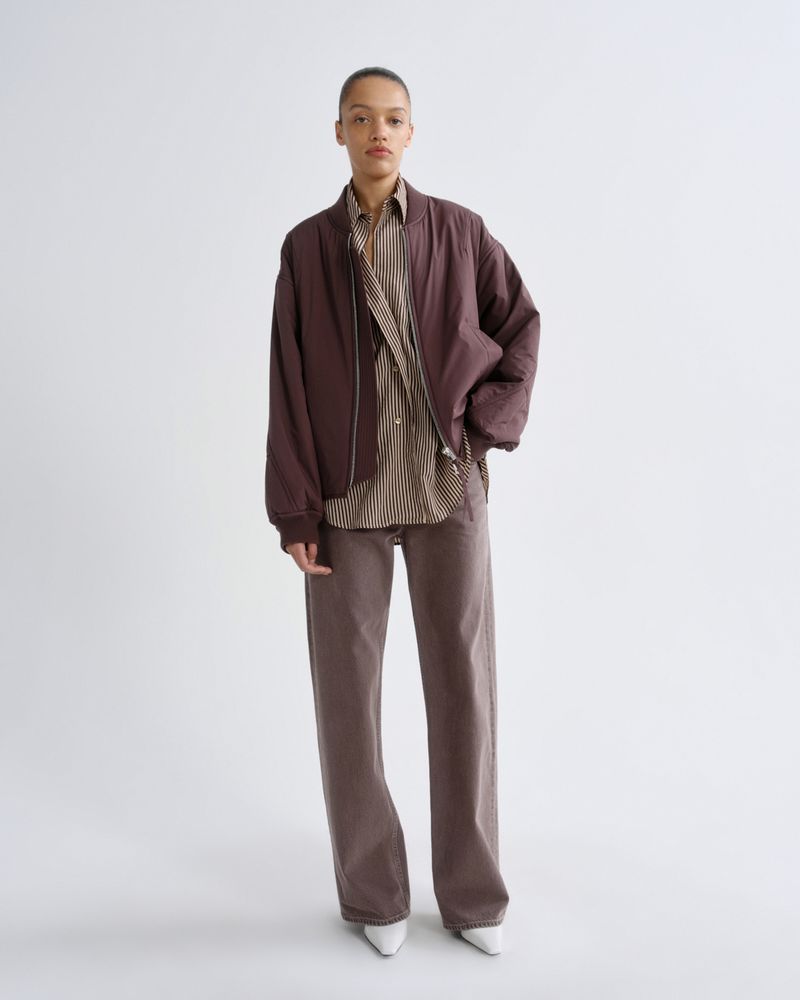 Person wearing a brown jacket and pants with a white background