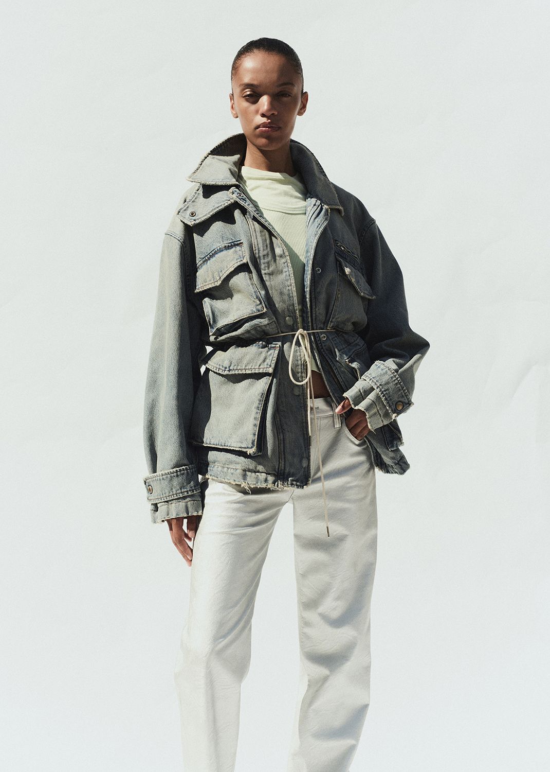 Person wearing a layered outfit with a denim jacket and vest on a plain background