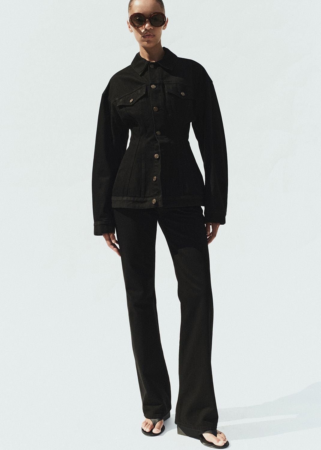 Person wearing a black jacket and pants on a white background